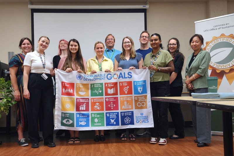 The sustainability team poses proudly with the SDGs poster