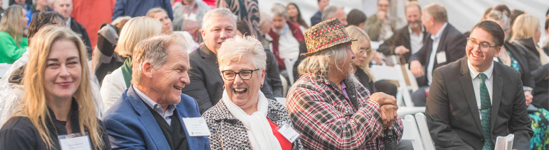 A UFV celebration with a row of seated guests smiling and engaging with one another