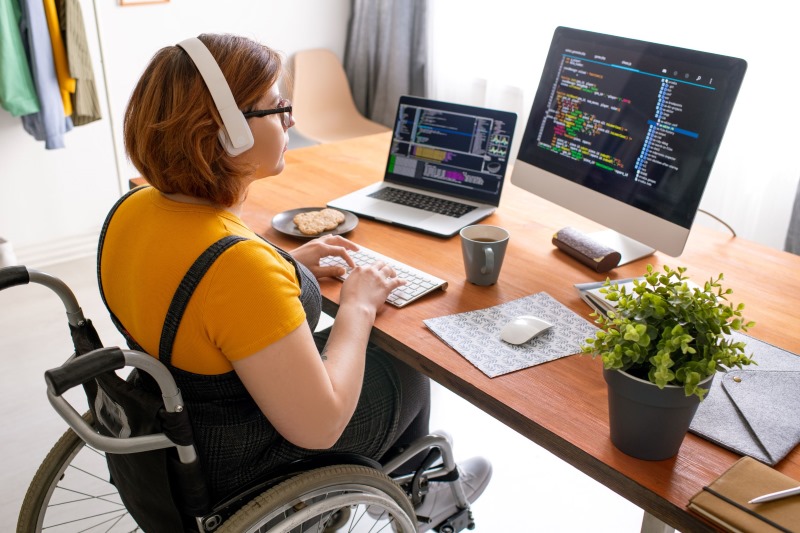 A computer programmer at a workstation, sitting in a wheelchair