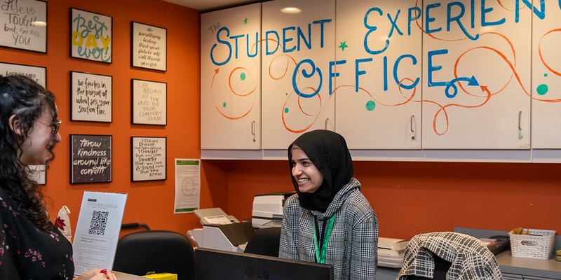 A student volunteer at the Student Experience lounge greets a student