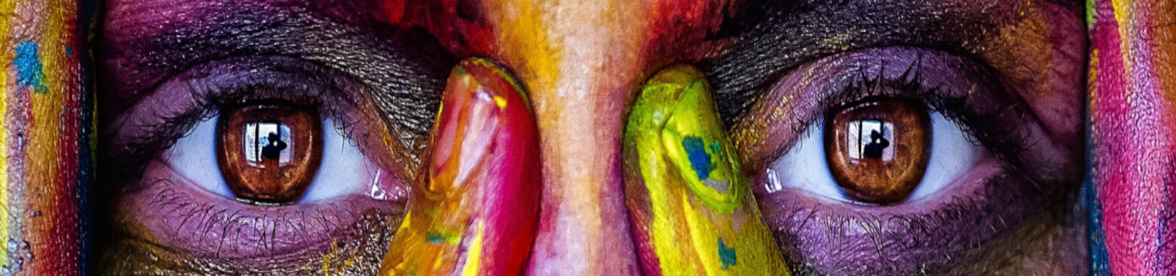Close up of a painted face with painted hands framing the eyes.